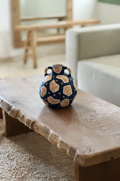 ואזה נייבי עגולה עם עיטורים בגוון שמנת על שולחן עץ