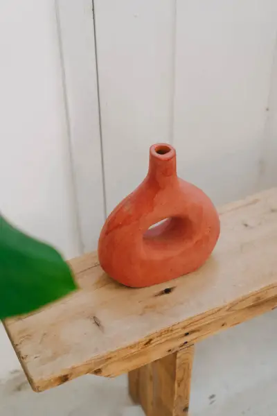 כלי חרס מרוקאי אדמדם עם חלל פתוח על ספסל עץ